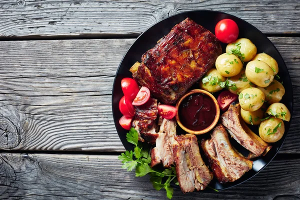 Grilled pork ribs on a black plate — Stock Photo, Image