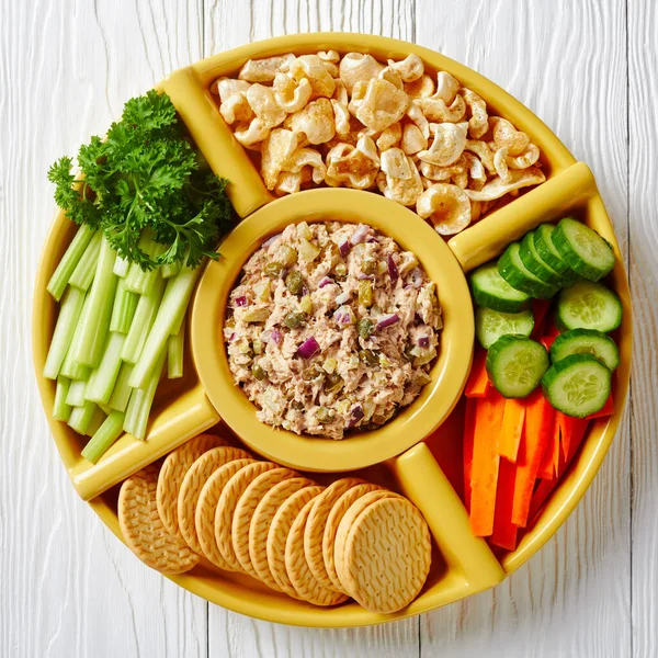 No-Cook Tuna capers pickles Spread set served with carrots and celery sticks, sliced fresh cucumber, crackers and pork rinds in bowls on a white wooden table, Philippines cuisine, flat lay,