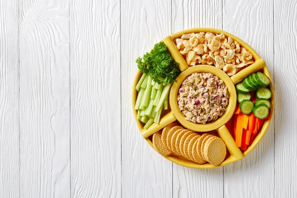 No-Cook Tuna capers pickles Spread set served with carrots and celery sticks, sliced fresh cucumber, crackers and pork rinds in bowls on a white wooden table, Philippines Style, flat lay, free space