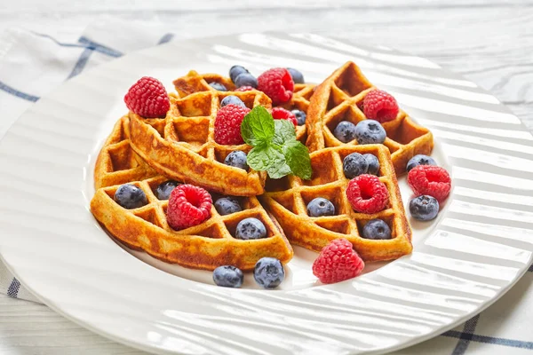 oatmeal banana waffles served with berries and honey on a white plate on a wooden table with  berries landscape view from above, close-up