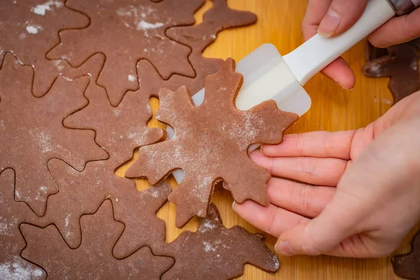 Star-shaped cake is lifted by a woman\'s hands with a white spatula, the preparation for Christmas pastries