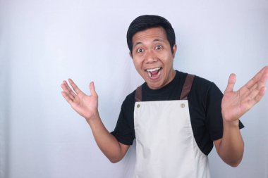 Funny shocked expression young asian man, barista, bartender, barman employee in brown apron black tshirt work in coffee shop spread hands