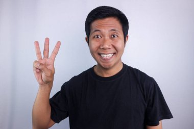 Smiling face expression asian man giving four finger signs isolated on white background.