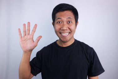 Smiling face expression asian man giving two finger signs isolated on white background.