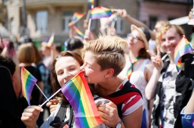 KYIV, UKRAINE 18 Haziran 2017: Gökkuşağı bayraklı kız LGBT cemaati tarafından düzenlenen Eşitlik Yürüyüşü sırasında başka bir kızı öpüyor