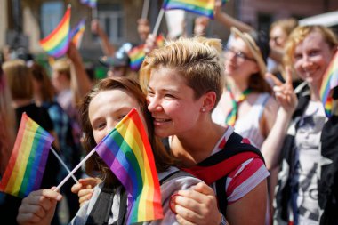 KYIV, UKRAINE 18 Haziran 2017: Gökkuşağı bayraklı kız LGBT cemaati tarafından düzenlenen Eşitlik Yürüyüşü sırasında başka bir kızı öpüyor