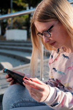 Anapa, Rusya Federasyonu - 2 Mayıs 2018, Genç kız Nintendo anahtarı konsolda oyun oynama. El Nintendo anahtarıyla açık çocuk. 