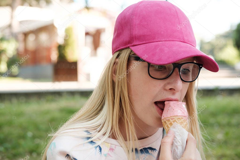  blond girl, teenager girl in eyeglasses eating ice cream. Childhood, summer, vacation concept