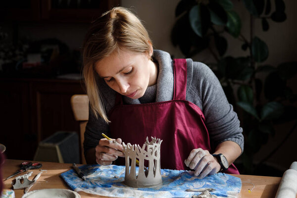 Woman potter making ceramic tree composition on the pottery workplace. Ceramist modeling on pottery workshop.