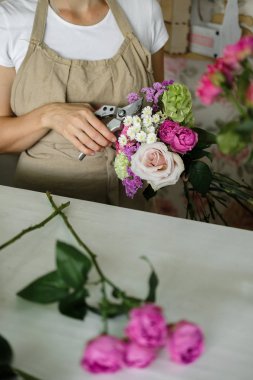kadın çiçekçi buket pembe çiçek kapalı yapma. Kadın çiçekçi çiçekçi gül buketi hazırlanıyor. Girişimcilik, küçük işletme, işyeri kavramı 