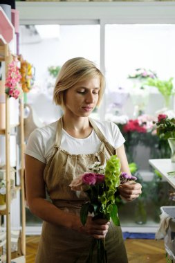 kadın çiçekçi buket pembe çiçek kapalı yapma. Kadın çiçekçi çiçekçi gül buketi hazırlanıyor. Girişimcilik, küçük işletme, işyeri kavramı 