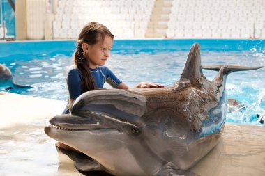 Çok dokunaklı ve şişe burunlu yunus ile sarılma çocuk. Kucaklayan ve sahne alanı'nda yunus sevecen küçük kız. Yunus terapisi destekli