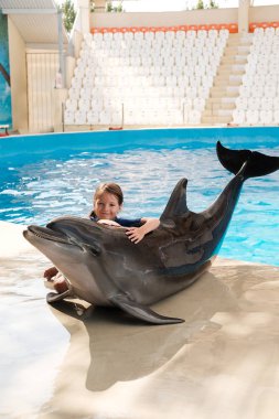 Şişe burunlu yunus ile sarılma evlat. Sahne Alanı'nda küçük kız kucaklayan yunus. Yunus terapisi destekli