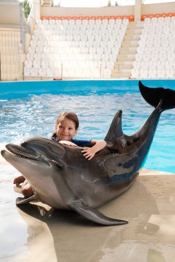 Şişe burunlu yunus ile sarılma evlat. Sahne Alanı'nda küçük kız kucaklayan yunus. Yunus terapisi destekli