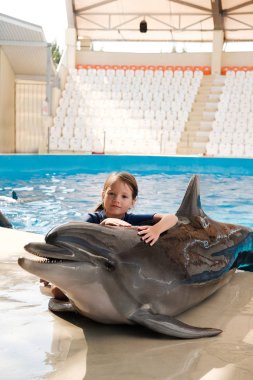 Şişe burunlu yunus ile sarılma evlat. Sahne Alanı'nda küçük kız kucaklayan yunus. Yunus terapisi destekli