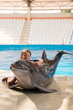 Şişe burunlu yunus ile sarılma evlat. Sahne Alanı'nda küçük kız kucaklayan yunus. Yunus terapisi destekli