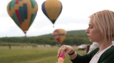 kabarcık ve arka plan üzerinde üç renkli aerostat balon üfleme kadın