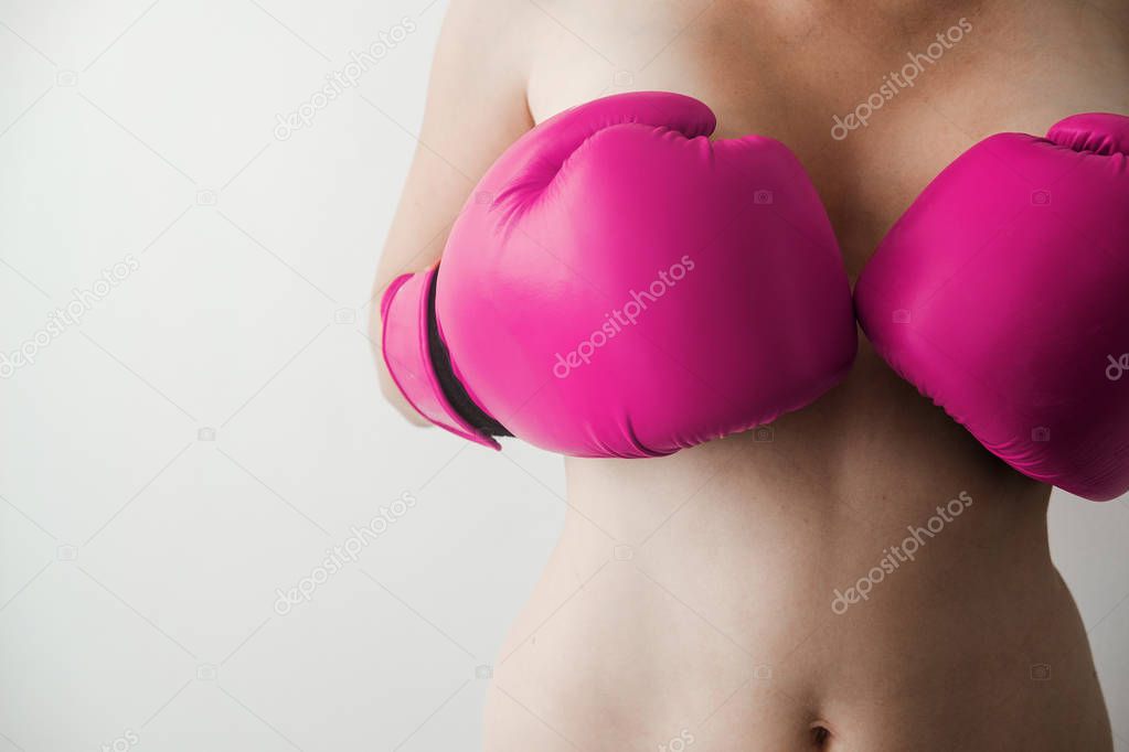 Naked woman covers the bare breast pink boxing gloves. Sexy and strong. Feminism, girl power, fight, gender, woman rights concept 