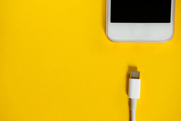 스마트폰은 노란색 바탕에 케이블을 충전기에 연결합니다 최고의 있습니다 텍스트에 공간을 — 스톡 사진