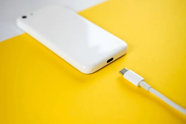 스마트폰은 노란색 바탕에 케이블을 충전기에 연결합니다 텍스트에 공간을 — 스톡 사진
