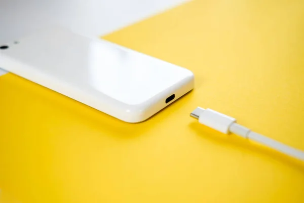 스마트폰은 노란색 바탕에 케이블을 충전기에 연결합니다 텍스트에 공간을 — 스톡 사진
