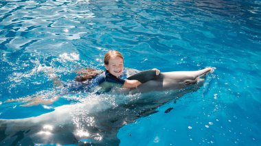 kız mavi su şişe burunlu yunuslar ile yüzme. Yunus terapisi destekli