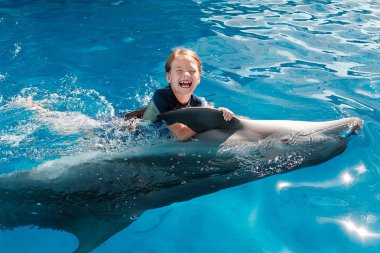 kız mavi su şişe burunlu yunuslar ile yüzme. Yunus terapisi destekli