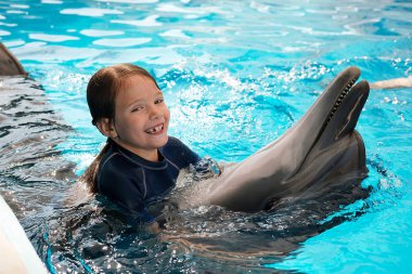 Kız mavi su şişe burunlu yunus ile yüzme. Yunus terapisi destekli