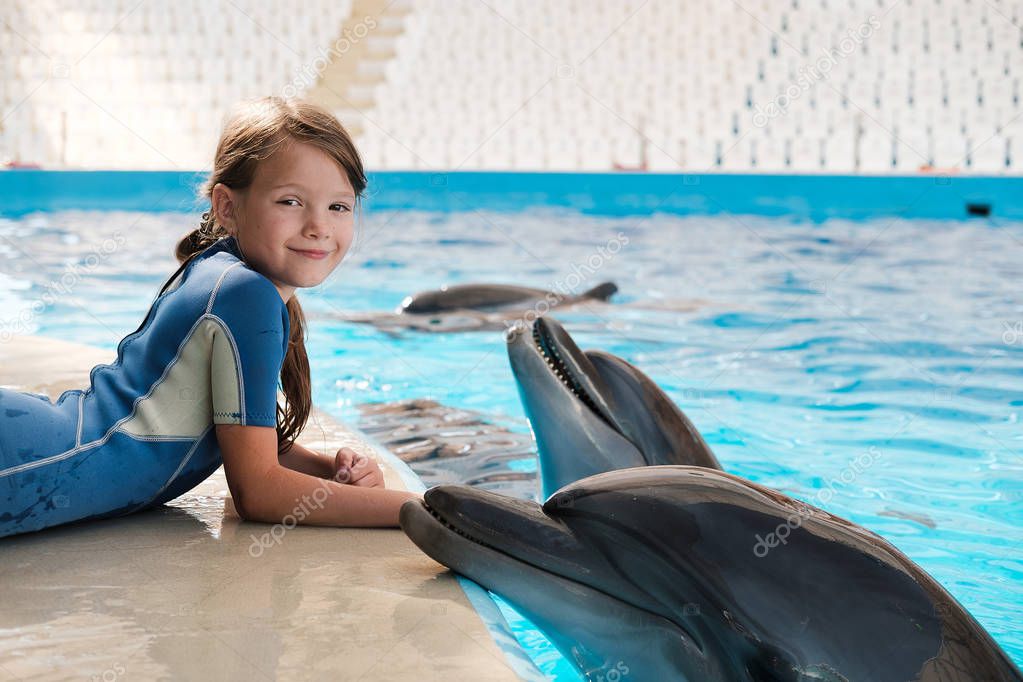 Girl swimming with bottlenose dolphins in blue water. Dolphin Assisted Therapy