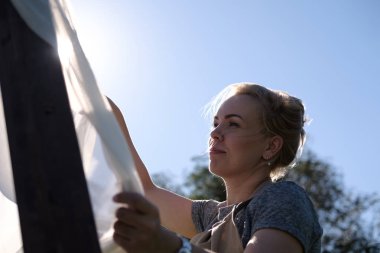 Kadın asılı perdeyi avlu üzerinde. Kadın tasarımcı tatil için hazırlık düğün kemer açık havada, dekorasyon