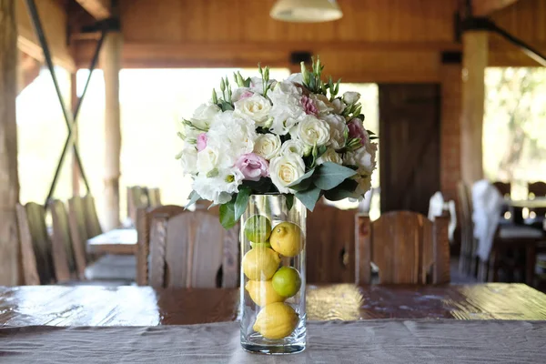 composition of flowers and fruit indoor. decorations of roses, lemons and limes at table