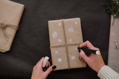 Kadın çizim kar taneleri kağıt üzerinde siyah arka plan üzerinde Noel kutu hediye paketi. Erkek hediyeleri kış tatilleri için üzerinde boyama eller. Noel, yeni yıl, alışveriş, tatil kavramı hazırlık