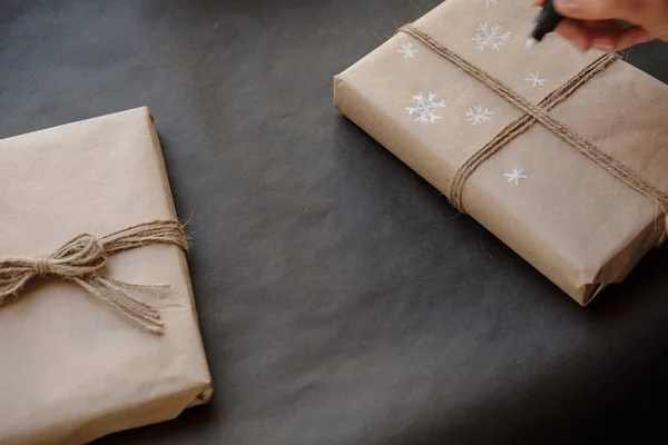 女性紙図面雪片は 黒い背景にクリスマス ボックス ギフトをパッケージ化します 女性の手の冬休みプレゼントの絵します クリスマス ショッピング 休日の概念上での準備 — ストック写真