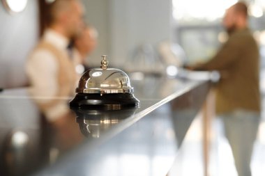 Modern lüks otel resepsiyon Counter Resepsiyon Bell ile. Bell resepsiyonda bulma hizmeti. Gümüş ara bir çan masada, resepsiyonistler arka plan üzerinde. Otel Heck. Kavramı.