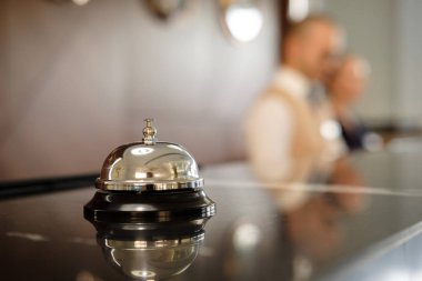 Modern lüks otel resepsiyon Counter Resepsiyon Bell ile. Bell resepsiyonda bulma hizmeti. Gümüş ara bir çan masada, resepsiyonistler arka plan üzerinde. Otel Heck. Kavramı.