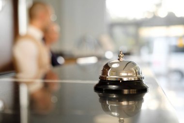 Modern lüks otel resepsiyon Counter Resepsiyon Bell ile. Bell resepsiyonda bulma hizmeti. Gümüş ara bir çan masada, resepsiyonistler arka plan üzerinde. Otel Heck. Kavramı. 