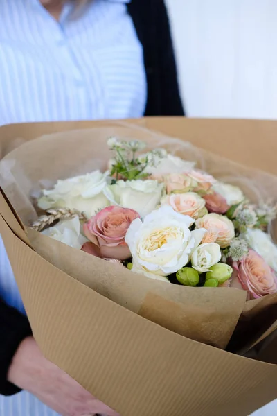 Bouquet of white and beige Roses. Woman Florist holding bouquet of Flowers indoor. Female florist preparing bouquet in flower shop. Close up. Mother\'s Day and Valentine\'s Day concept