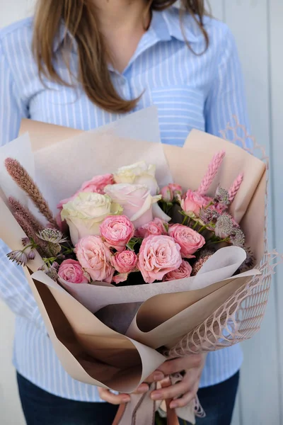 Bouquet of white and pink Roses. Woman Florist holding bouquet of Flowers indoor. Female florist preparing bouquet in flower shop. Close up. Copy space. Mother\'s Day and Valentine\'s Day concept