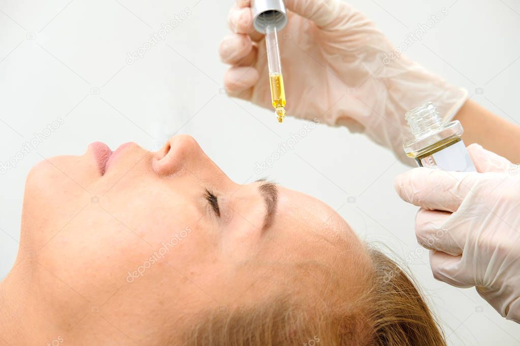 Cosmetologist and Female Patient in beauty salon. Hyaluronic Acid, hydration skin, drops Bottle, Botox. Facial Treatment Essence Skin Care Cosmetic, Face Rejuvenation. Close up