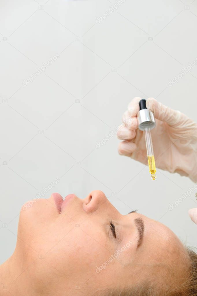 Cosmetologist and Female Patient in beauty salon. Hyaluronic Acid, hydration skin, drops Bottle, Botox. Facial Treatment Essence Skin Care Cosmetic, Face Rejuvenation. Close up