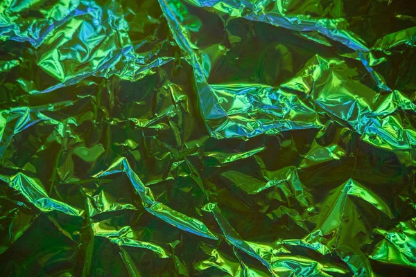 Holographic real texture in iridescent blue green colors with folds and irregularities. Holographic color wrinkled foil. Crumpled Abstract texture background