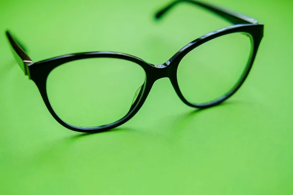 Black frame eyeglasses on green background. Myopia (nearsightedness), Short sighted or presbyopia (Farsightedness) eyeglasses.  Close up