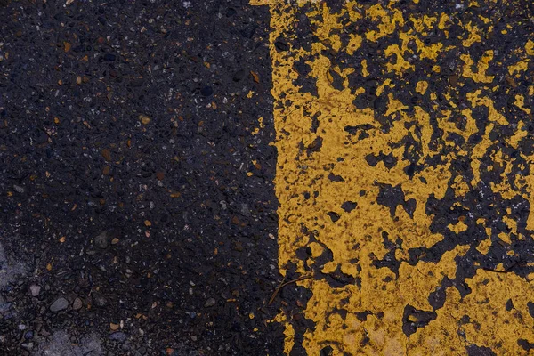 Peeling paint on asphalt and road markings. Asphalt crosswalk surface texture detail with peeling old and yellow paint. Background