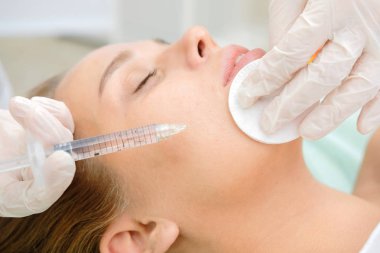 Mezoterapi yapan kozmetolog. Şırınga ve iğne, yüz kozmetik güzellik enjeksiyonu. Kadın hasta güzellik te yüz gençleştirme prosedürü alıyor. Hırdavat kozmetolojisi, Hyaluronik Asit.  