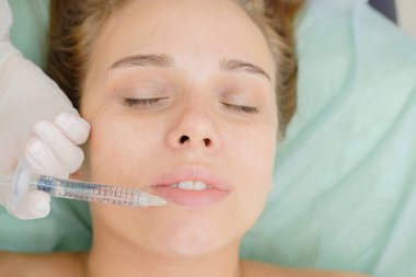 Dudak dolgu enjeksiyonları. Tombul dudaklar büyütme. Güzellik plastik. Kadın hasta için mezoterapi yapan kozmetolojist. Şırınga ve iğne, yüz kozmetik güzellik enjeksiyonu.