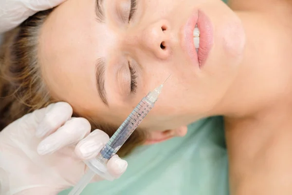 Cosmetologist making mesotherapy. Syringe and needle, facial cosmetic beauty injection. Woman patient is getting face rejuvenation procedure at beautician. Hardware cosmetology, Hyaluronic Acid.