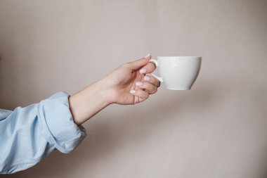Bir fincan kahve tutan kadın. Bej arka planda siyah çay fincan ile Kadın elleri. Yakın çekim