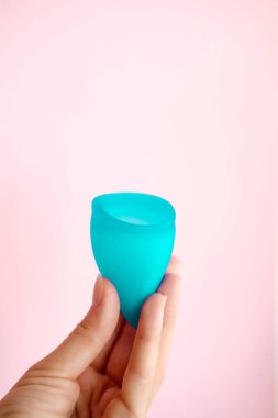 Kadın elleri pembe arka plan üzerinde mavi adet fincan tutarak. Dönem tampon yerine kadın hijyeni alternatif ürün. Adet, kritik günler, kadın dönemleri. Sıfır atık, eko, ekoloji