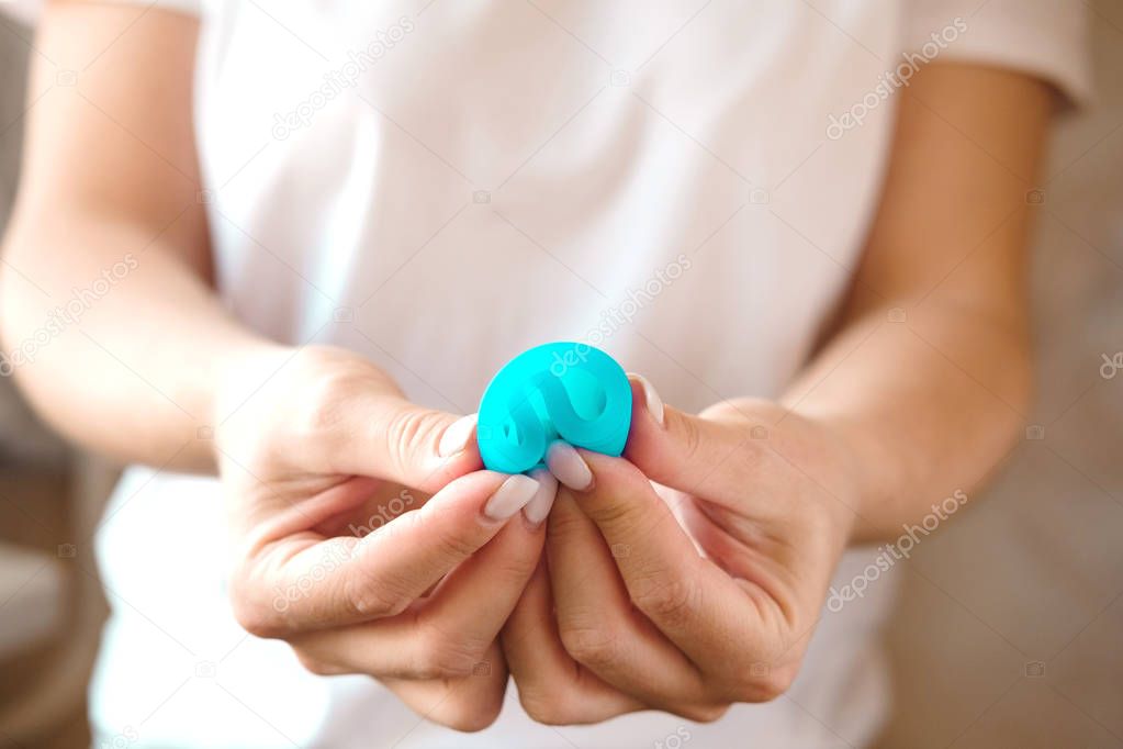 Woman holding in hands folded blue menstrual cup. Feminine hygiene alternative product instead of tampon during period. Menstruation, critical days, women periods. Zero waste, eco, ecology. Close up