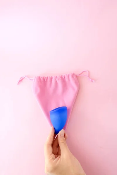 女性手与蓝色月经杯和袋在粉红色的背景 袋形为子宫 女性卫生替代产品 关键天 女人期 妇女健康概念 — 图库照片